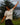 Smiling woman with arms raised outdoors wearing heather natural Campfire Nights short sleeve tee with Rock Life mountain logo, casual camping and hiking shirt for outdoor adventures