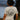 Back view of woman outdoors wearing heather natural Campfire Nights short sleeve tee with mountain and campfire graphic, casual camping and hiking shirt for outdoor adventures