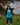 Woman smiling with arms outstretched outdoors wearing teal Campfire Nights tank top with campfire and mountain design, perfect for camping and adventure wear