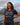Woman wearing navy Wake Up. Rock Life. Repeat. Adventure in Every Letter t-shirt, smiling outdoors with mountains and water in the background. National adventure lifestyle apparel.