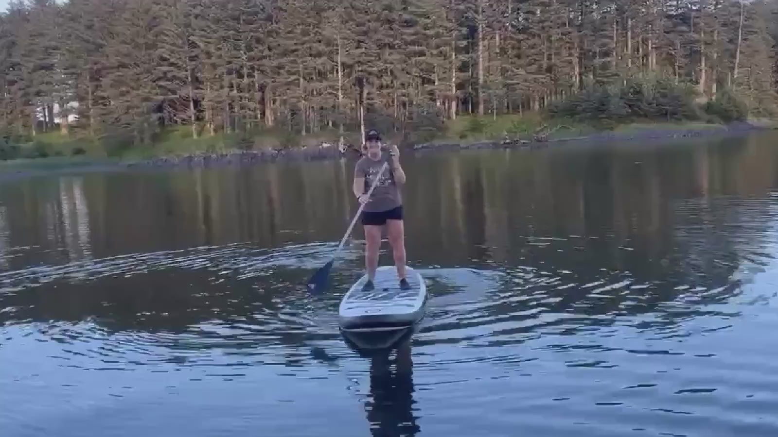 Woman wearing brown Rock Life Adventure in Every Letter tee and trucker hat while paddleboarding in Kodiak, Alaska